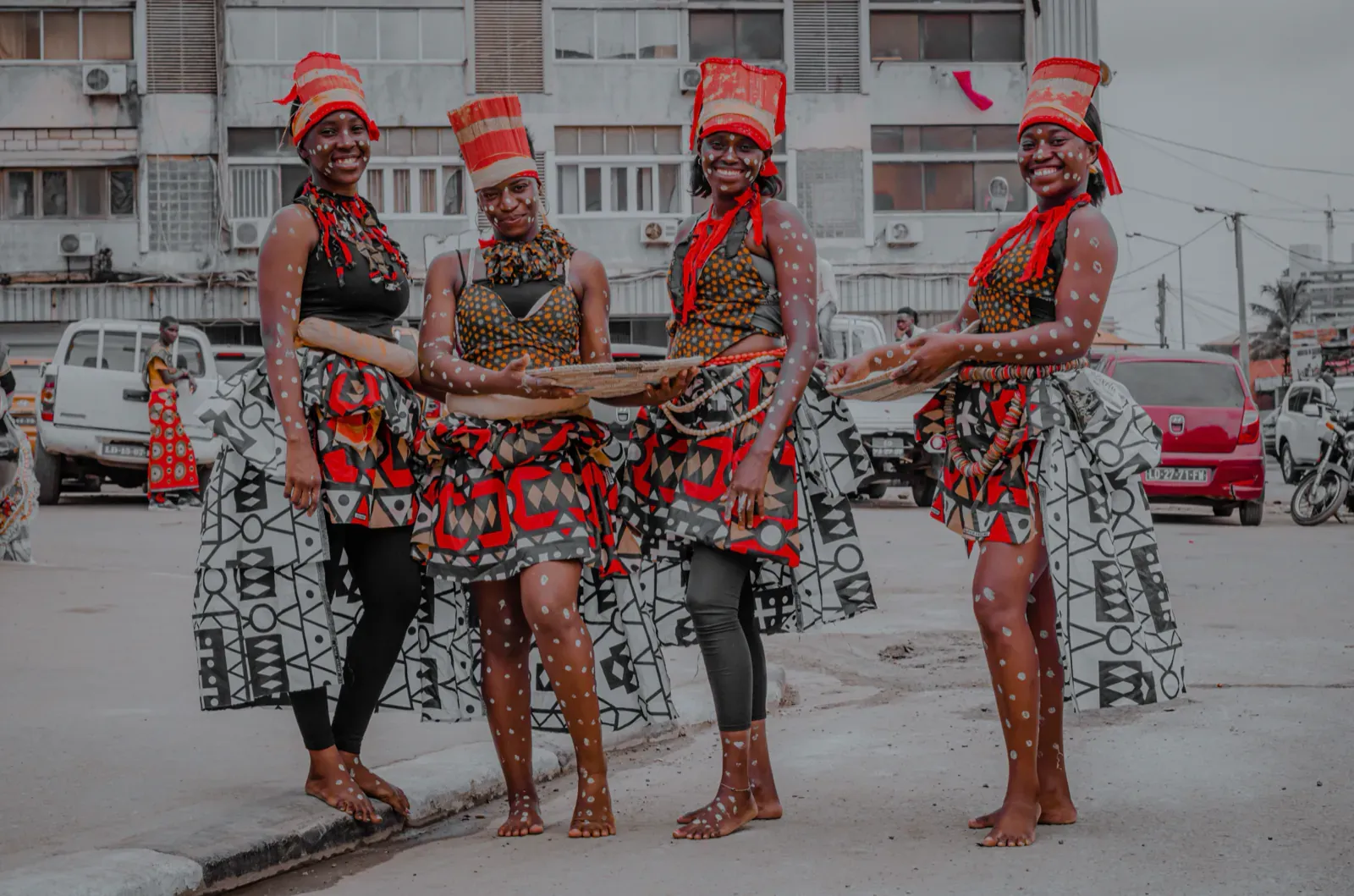 Four dancers in traditional Angolan dress on a street in Luanda.